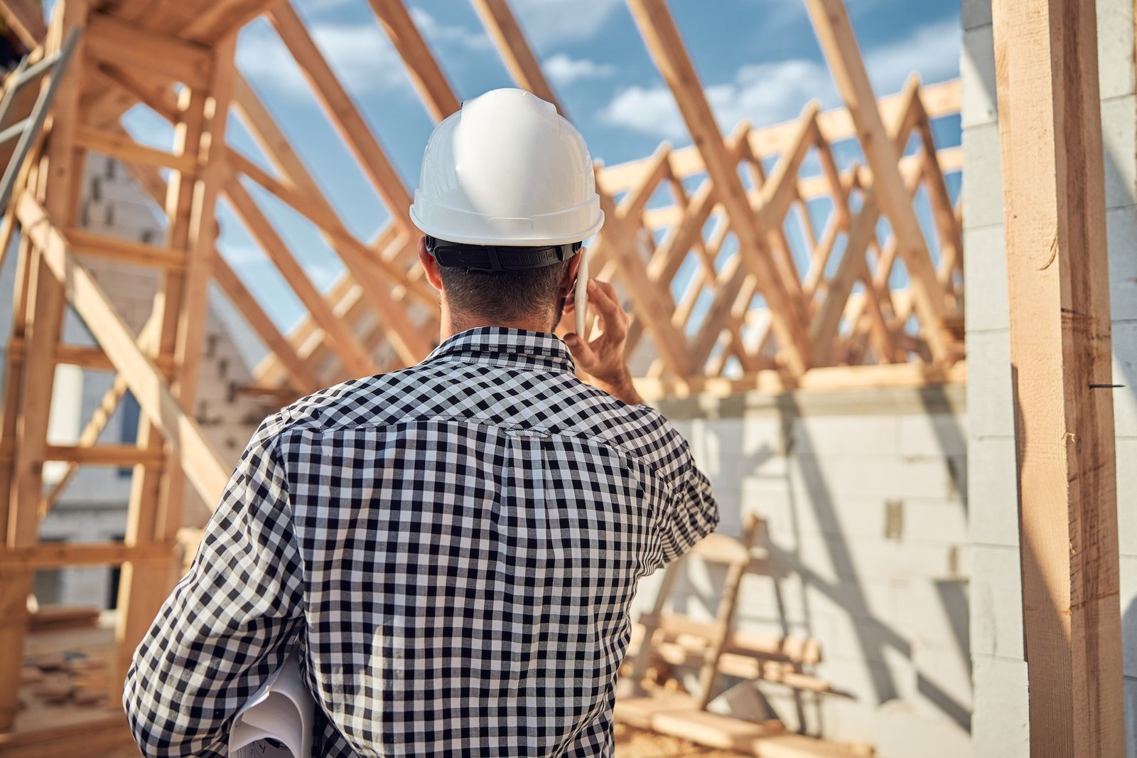 Young contractor in a hard hat talking on the phone